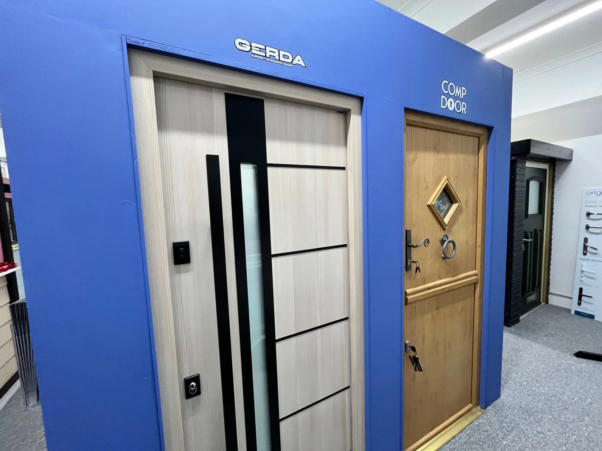Silver GERDA entrance door beside a timber-effect CompDoor showroom display