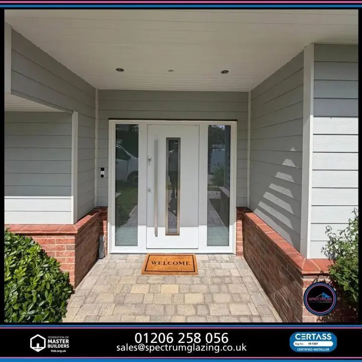White Gerda Optima 60 front door with a tall silver pull handle and two full-height sidelights in a grey-clad porch in Wickham Bishops